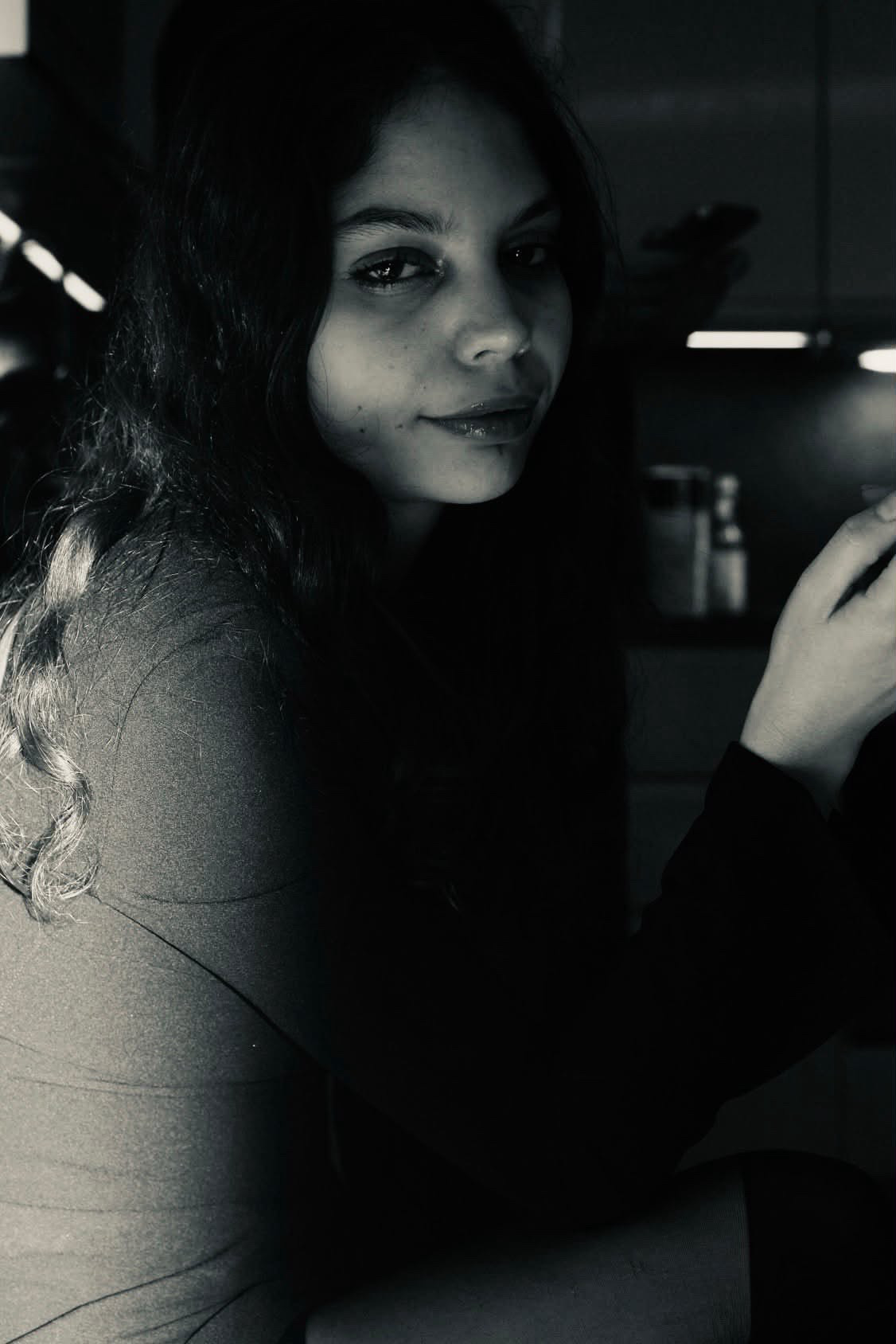 Portrait en noir et blanc de Leila Mouttaqui, regard par-dessus l'épaule, éclairage de côté
